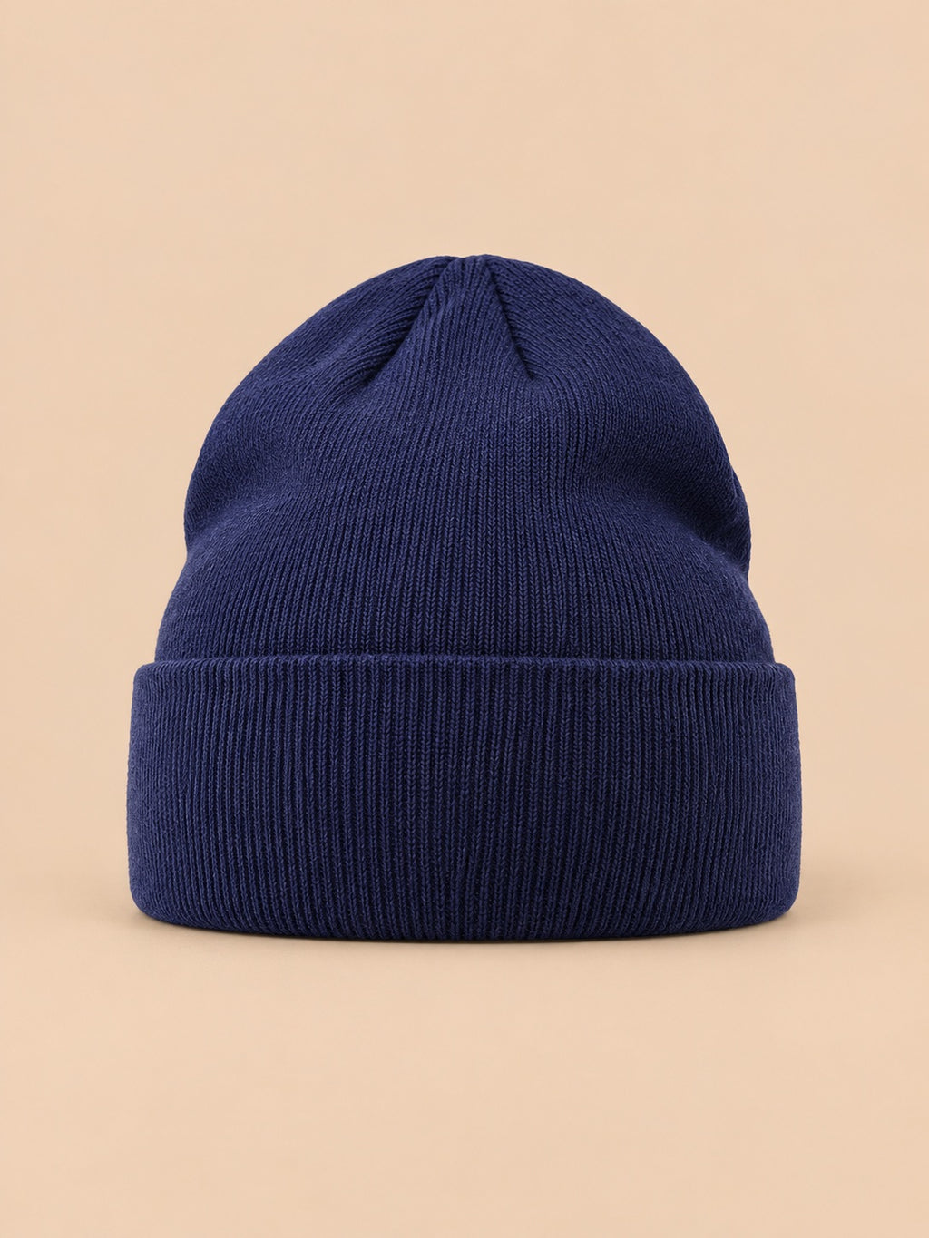 Bonnet uni classique en maille bleu marine, vue de face sur fond pêche sable