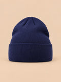 Bonnet uni classique en maille bleu marine, vue de face sur fond pêche sable