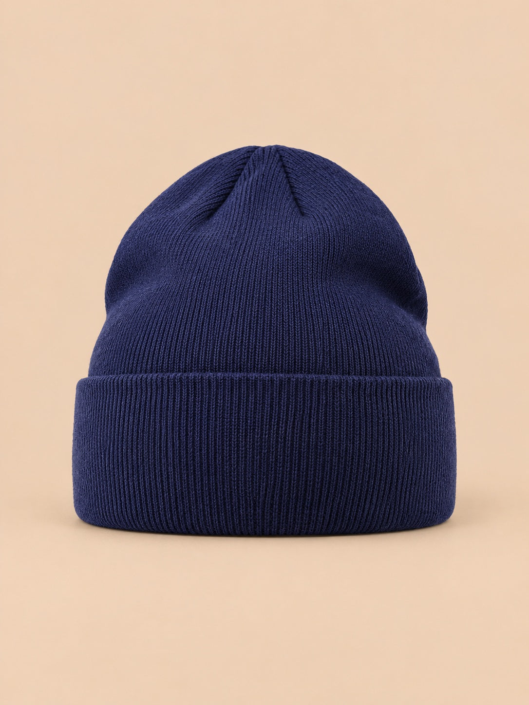 Bonnet uni classique en maille bleu marine, vue de face sur fond pêche sable