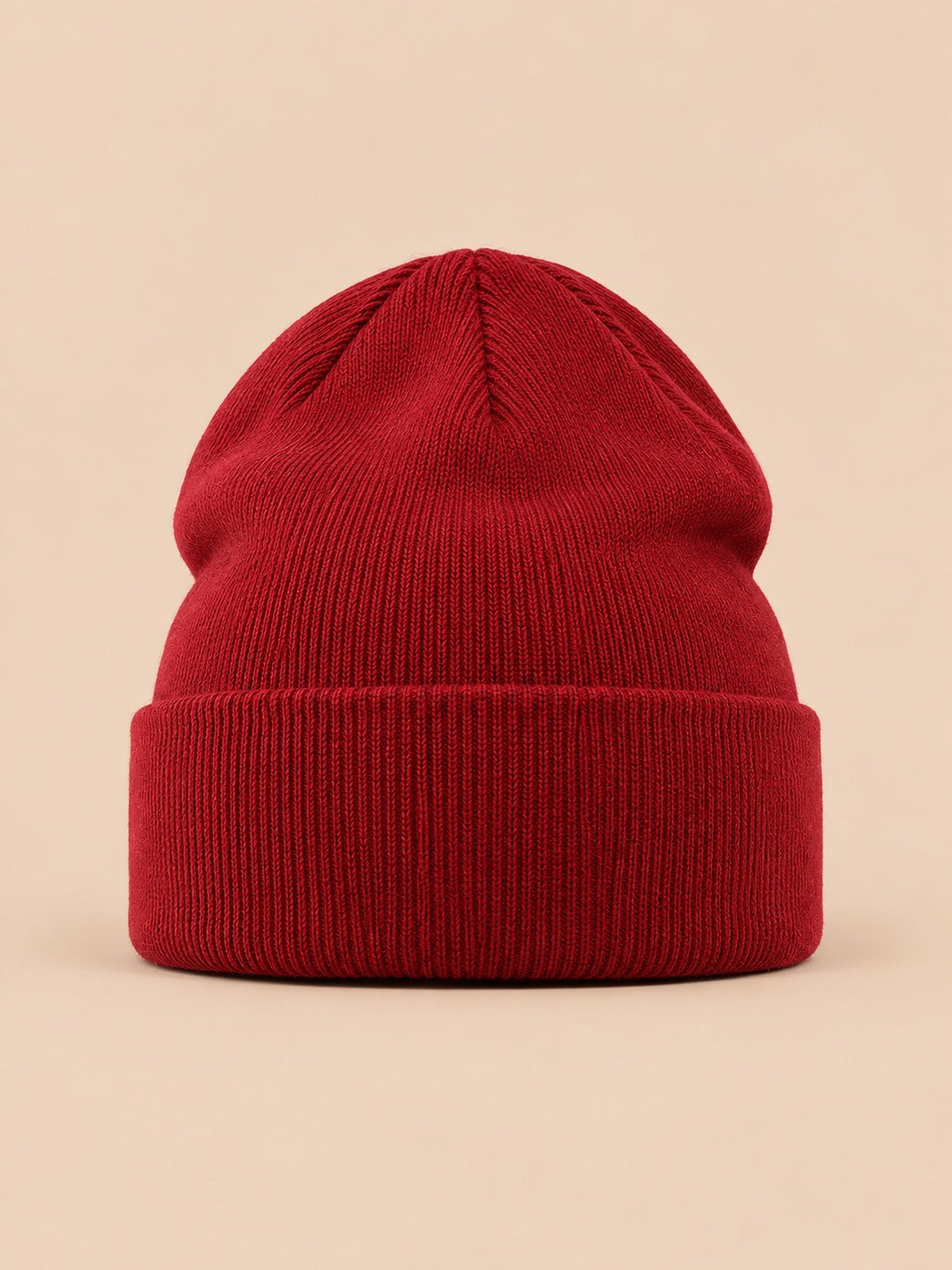 Bonnet uni classique en maille bordeaux, vue de face sur fond pêche sable