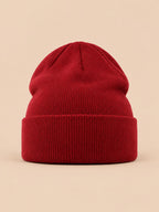 Bonnet uni classique en maille bordeaux, vue de face sur fond pêche sable