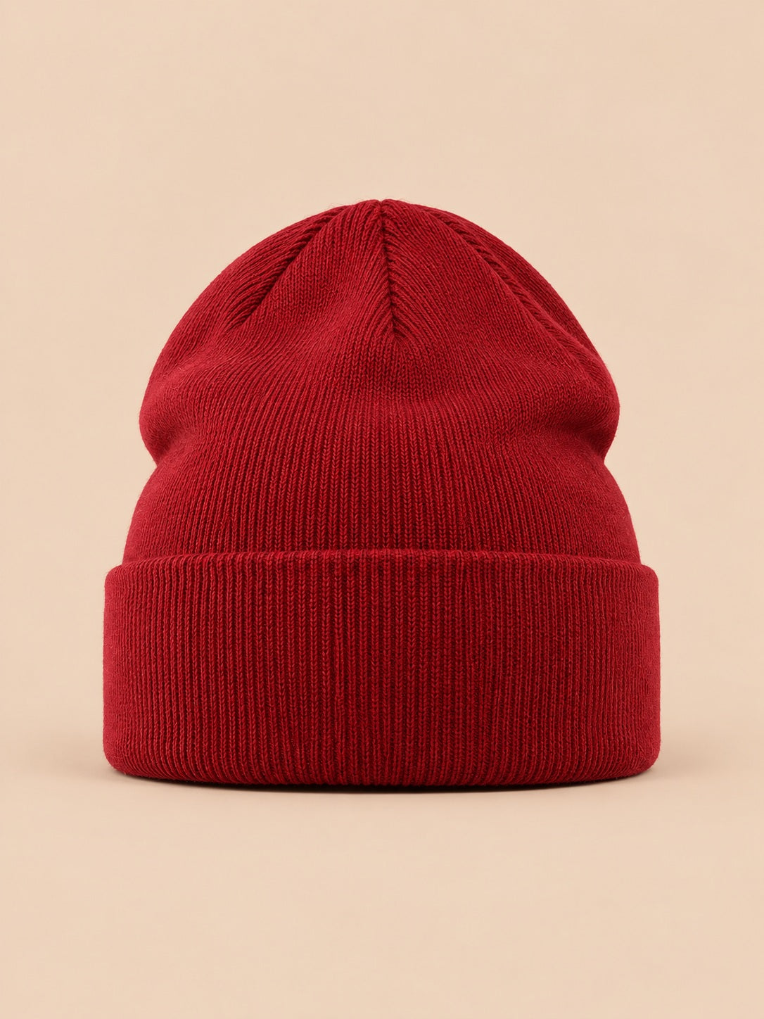 Bonnet uni classique en maille bordeaux, vue de face sur fond pêche sable