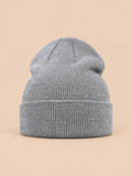 Bonnet uni classique en maille gris clair, vue de face sur fond pêche sable
