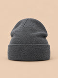 Bonnet uni classique en maille gris foncé, vue de face sur fond pêche sable