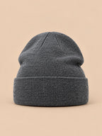 Bonnet uni classique en maille gris foncé, vue de face sur fond pêche sable