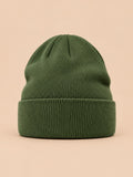 Bonnet uni classique en maille vert, vue de face sur fond pêche sable